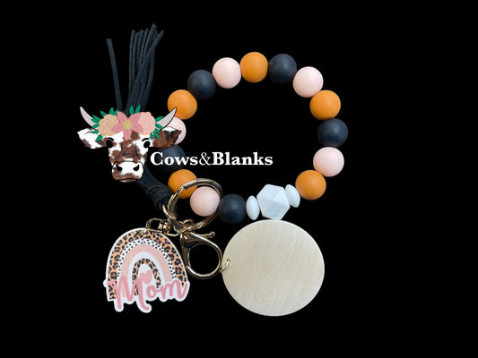 Mom's Trio of Soft Pink, Terracotta, and Black Silicone Stretch Beaded Wristlet Bracelet Keychain with a Wooden Leopard Print Rainbow Mom Charm with White Accent Silicone Beads.  Wristlet has Gold Hardware, a Matching Tassel,  and a Wooden Disc