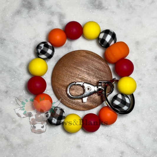 AUTUMN ORANGE PUMPKIN SILICONE BEADS WITH BLACK AND WHITE GINGHAM. SOID RED AND SOLID YELLOW ACCENT BEADED WRISTLET WITH WOODEN DISK