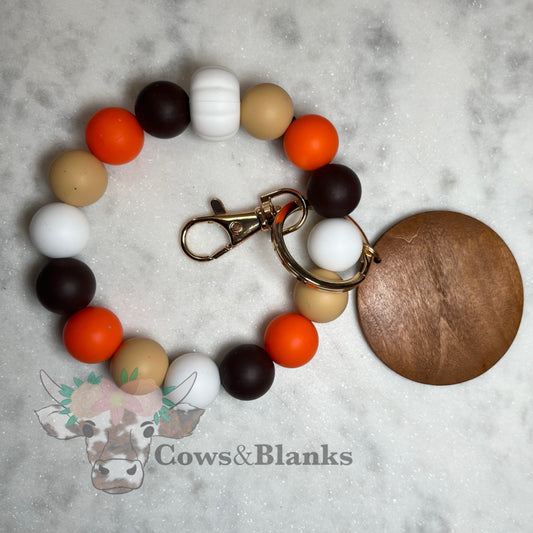 AUTUMN WHITE PUMPKIN SILICONE BEADS WITH MOCHA, ORANGE AND BEIGE ACCENT BEAD STRETCH WRISTLET BRACELET WITH WOODEN DISC