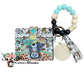 Wallet/Wristlet with Bessie the Cow on Cow-print Cardholder and with Aqua and Black Silicone Beads Paired with Wooded Beads Wristlet with Wooden Accent Bead and Matching Tassel with a Wooden Disc