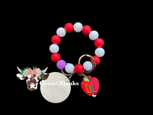 Red and White Silicone Stretch Beaded Wristlet Bracelet Keychain with a purple accent bead with a Red Apple With the Word "Teach" on it with Gold Hardware and a Wooden Disc